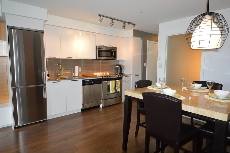 Modern executive kitchen featuring full-sized stainless steel appliances, built-in dishwasher, and electric range.