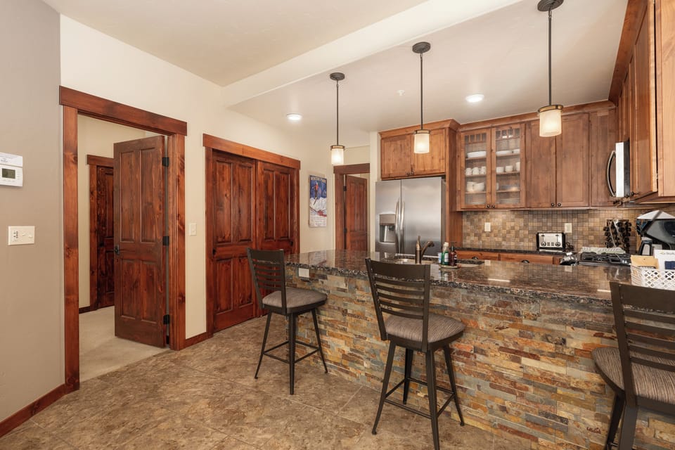 - Stone accented kitchen island with pendant lighting and high back seating - Warm wood tones and rustic finishes create a welcoming mountain lodge vibe - Great space for casual dining, card games, or morning coffee chats