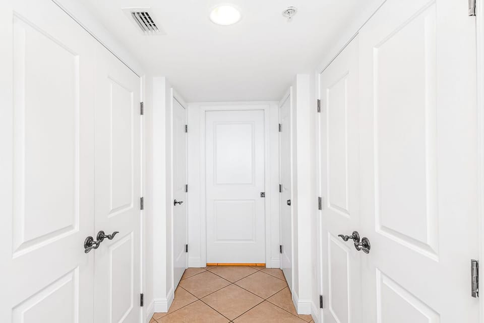 Your private hallway features elegant white doors and beautiful tile flooring, creating a sophisticated entrance to your retreat.