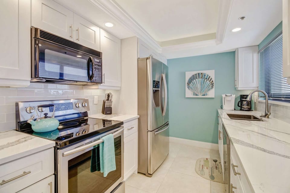 The kitchen is well stocked with cookware, dinnerware and many small electric appliances, including a Kuerig coffeemaker.