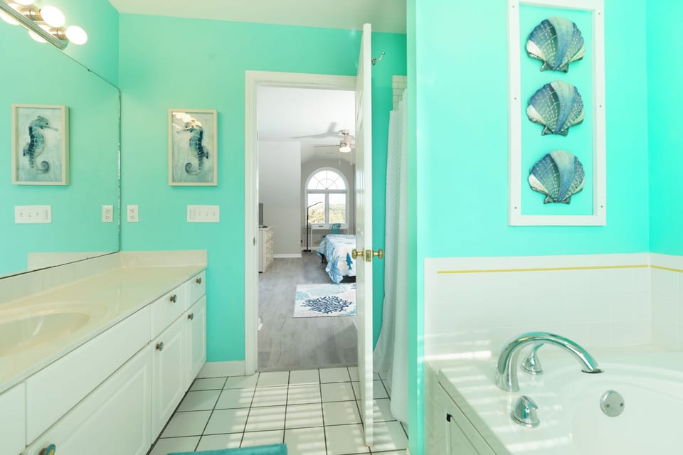 Immerse yourself in this vibrant sea-themed bathroom where turquoise walls and coastal artwork create your perfect ocean escape retreat.