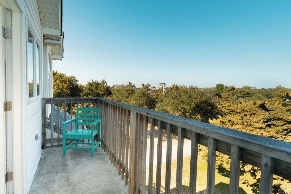 Relax on your private balcony with forest views and a bright turquoise chair perfect for morning coffee.