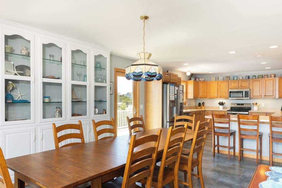 Gather everyone around this spacious dining table or cozy breakfast bar, where you can enjoy meals together in a bright, welcoming kitchen filled with natural light and coastal charm.
