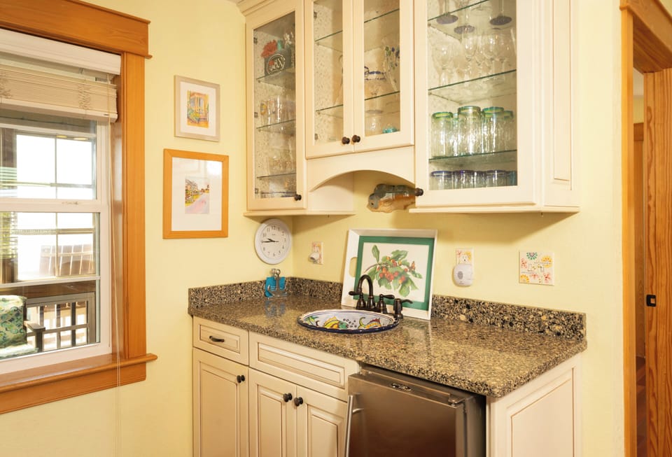 Your well-equipped kitchen awaits with gleaming granite counters, glass-front cabinets, and a dishwasher to make meal prep a breeze. Sunlight streams through, illuminating charming artwork and thoughtful details.