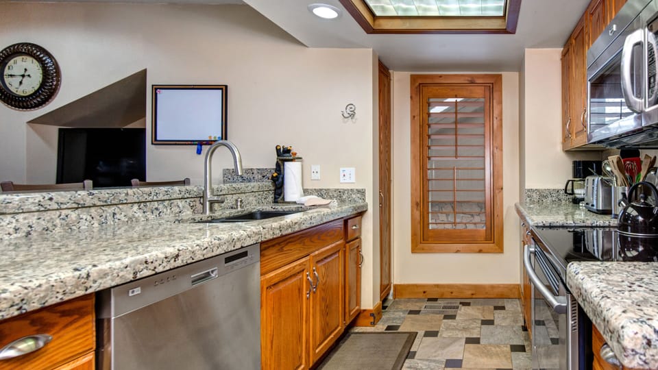 Enjoy this fully equipped kitchen featuring sleek granite countertops, a stainless steel dishwasher, and ample counter space. Perfect for preparing meals during your stay.