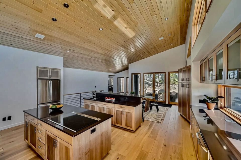 Spacious modern kitchen with double islands, vaulted ceiling, and natural wood finishes