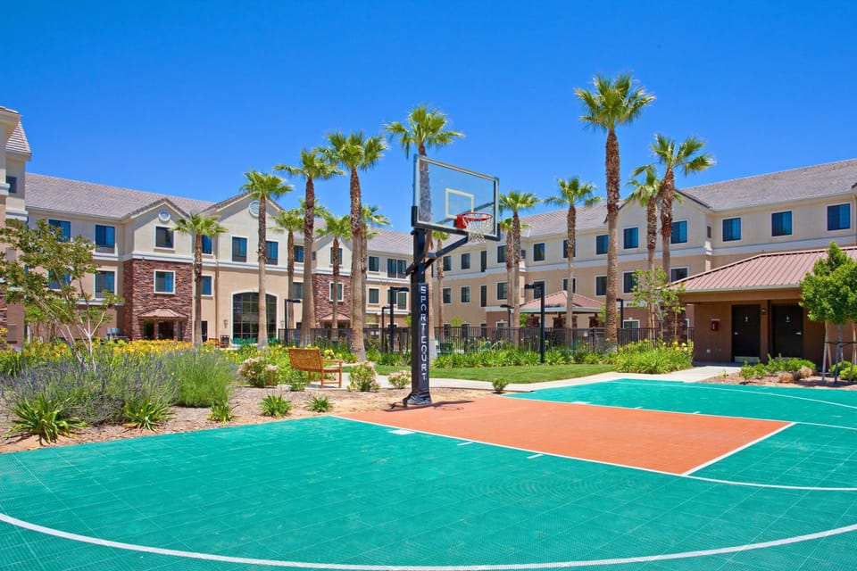 On-site basketball sport court with palm trees and hotel buildings.