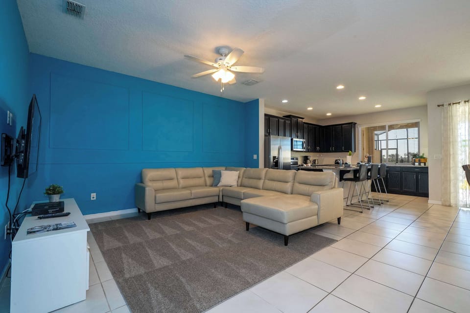 Relax in the open-concept living area-cozy sectional and bold blue accent wall-then gather in the modern kitchen with stainless appliances and a breakfast bar.