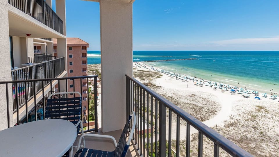 Enjoy the view from your balcony, featuring seating and a stunning landscape of beach umbrellas and clear waters