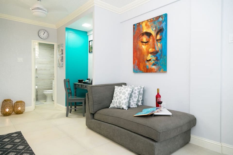 Cozy living nook w/ sofa, colorful art & small dining table beside a vibrant teal doorway