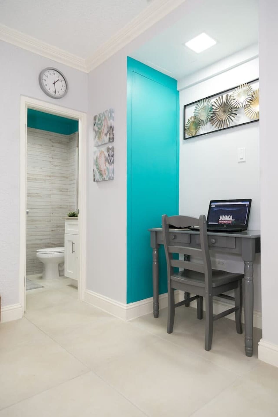 Cozy corner desk beside a bold teal doorway leading to the bathroom