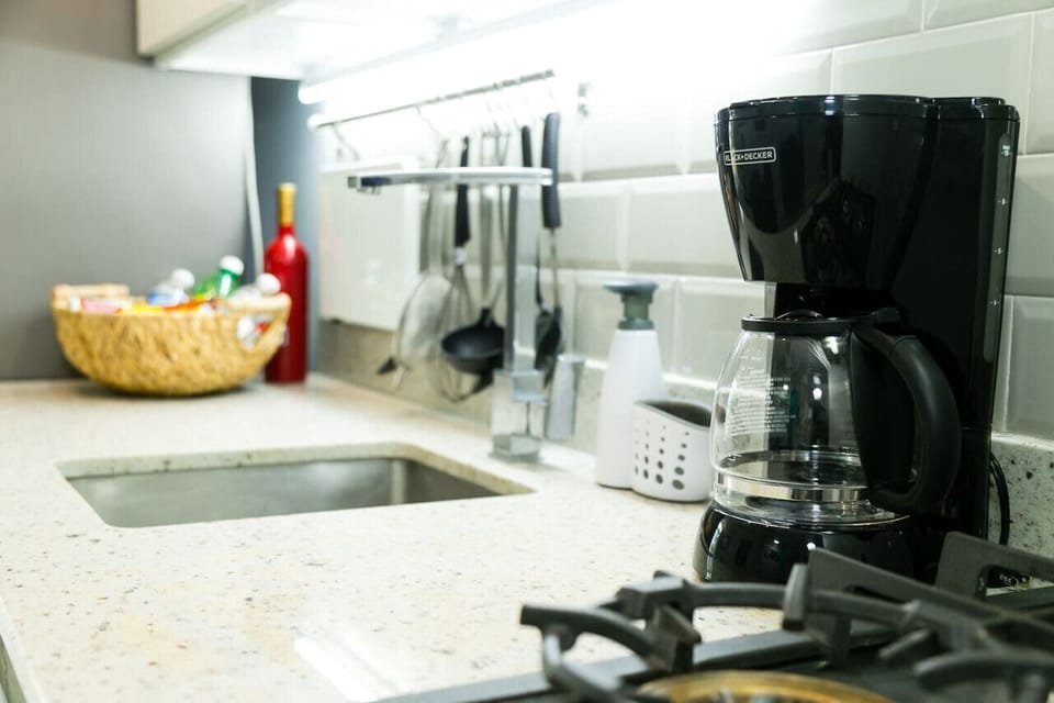 Kitchen counter w/ sink, coffee maker & utensils ready for simple meals