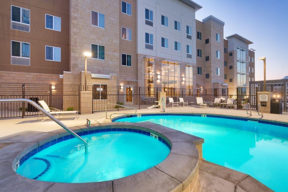 Outdoor pool deck with hot tub and lounge chairs.