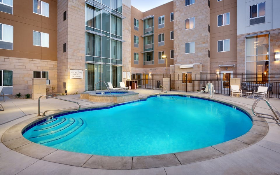Outdoor heated pool with hot tub and poolside seating.