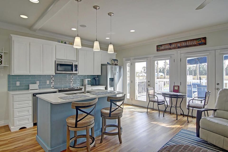 Gather in this bright open kitchen with island seating and dining nook where beach breezes flow through French doors to your deck.