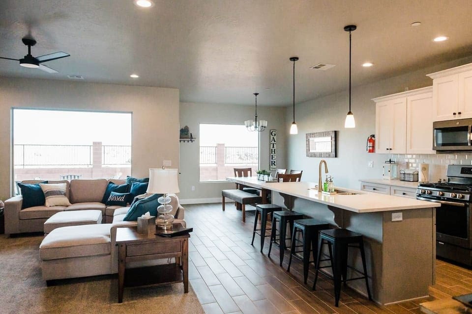 View of kitchen, living room and dining table with bar stools at counter