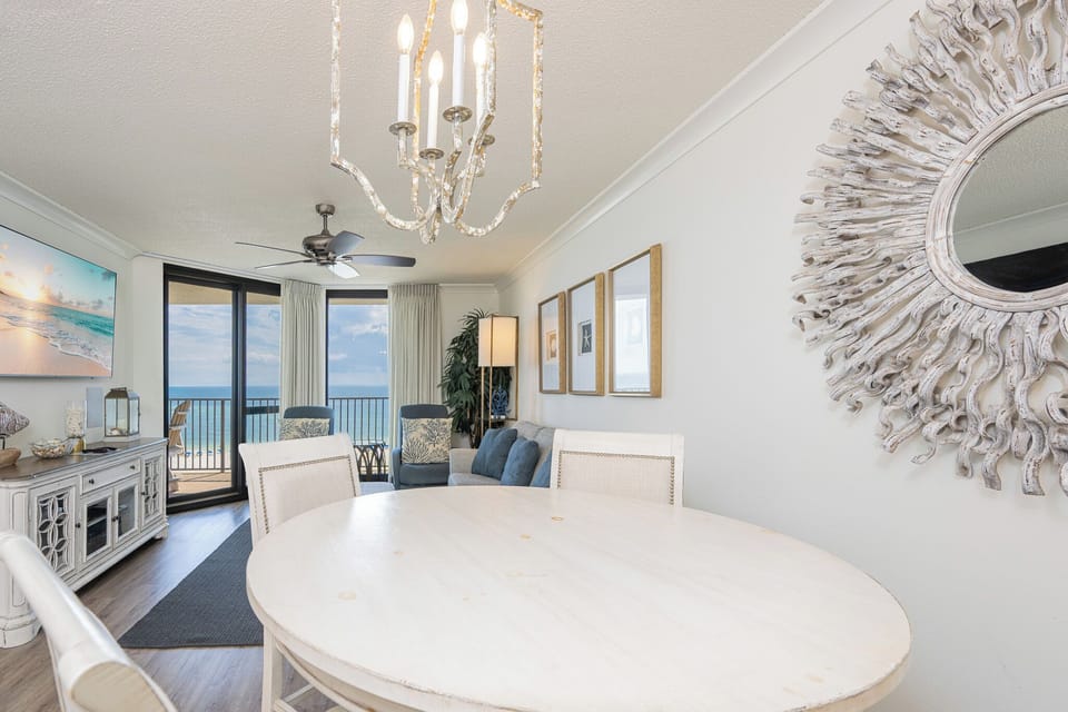 Bright dining area featuring a round table, stylish chandelier, and a view of the gulf through large sliding glass doors