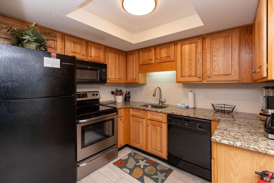 Kitchen featuring stainless and black appliances, warm wood cabinetry, and a stylish countertop for your culinary adventures