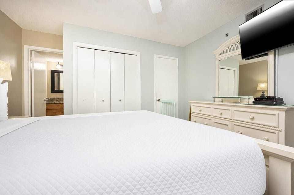 Guest bedroom featuring a king bed, a flat-screen TV, and a stylish dresser with a mirror