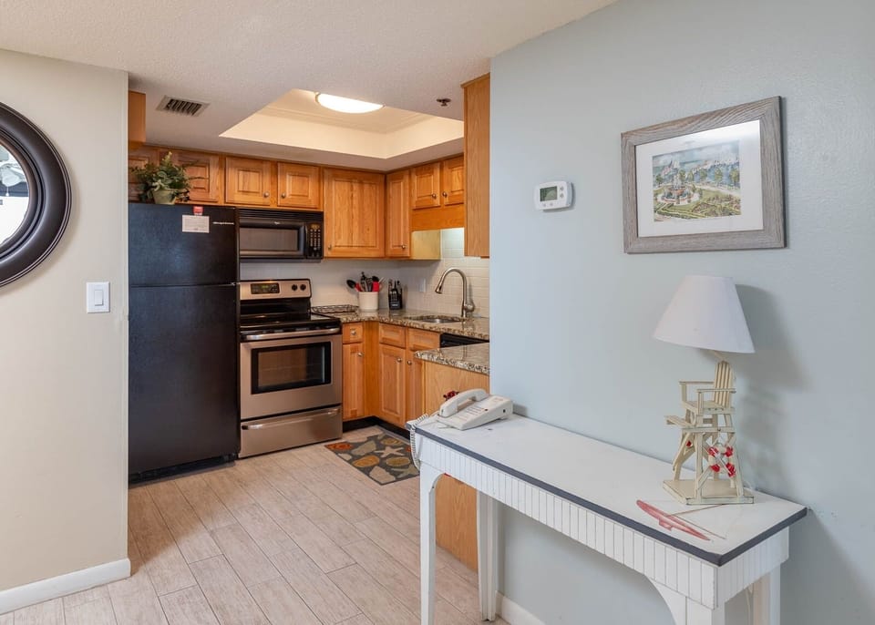 Kitchen featuring black and stainless appliances, granite countertops, and charming decor for a welcoming vacation experience