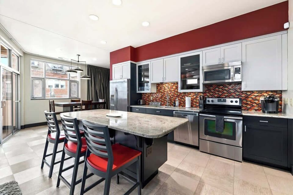 Sleek and modern with an island bar perfect for entertaining, the kitchen is fully stocked to fit any group's needs! Did someone say Razorback backsplash!? Featuring a vintage 'W Dickson St.' street sign.
