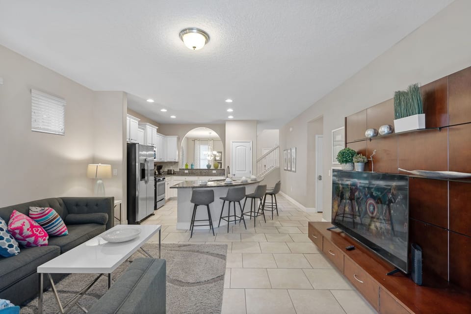 Equipped kitchen, comfy sofa, and large TV for entertainment in an open layout.