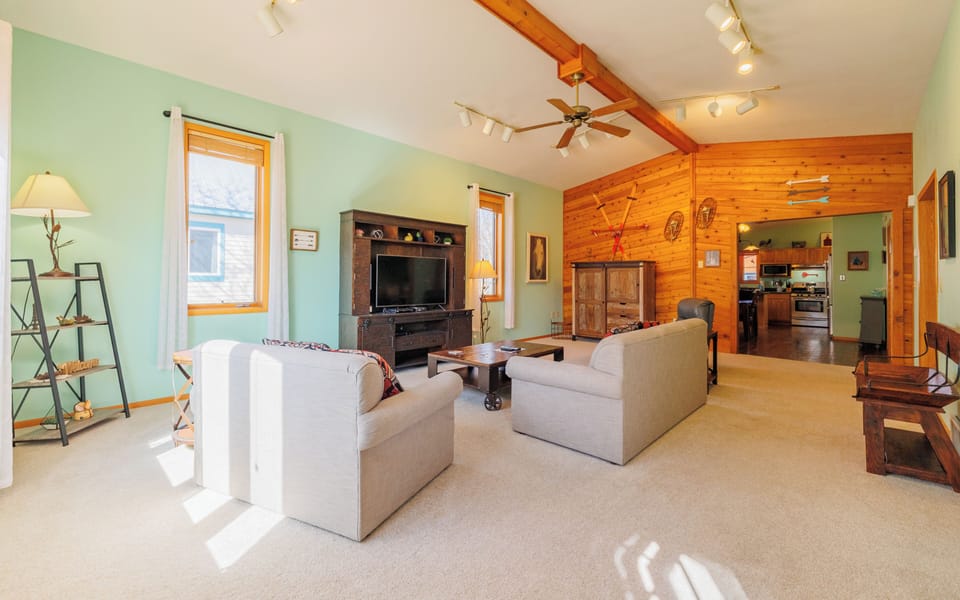 The living room features vaulted ceilings, natural wood finishes and comfortable funishings