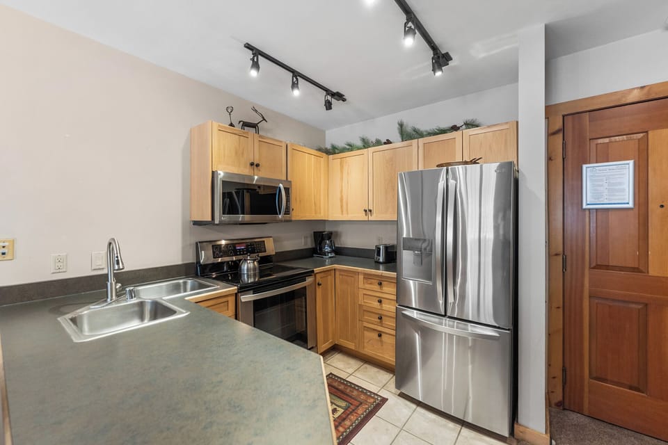 Your fully equipped kitchen awaits with stainless steel appliances, warm wood cabinetry, and everything needed for memorable meals.