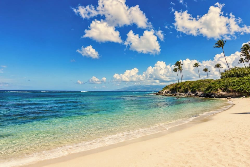 Relax on Maui’s secluded beach with soft golden sand, turquoise waters & swaying palms in pure tropical serenity