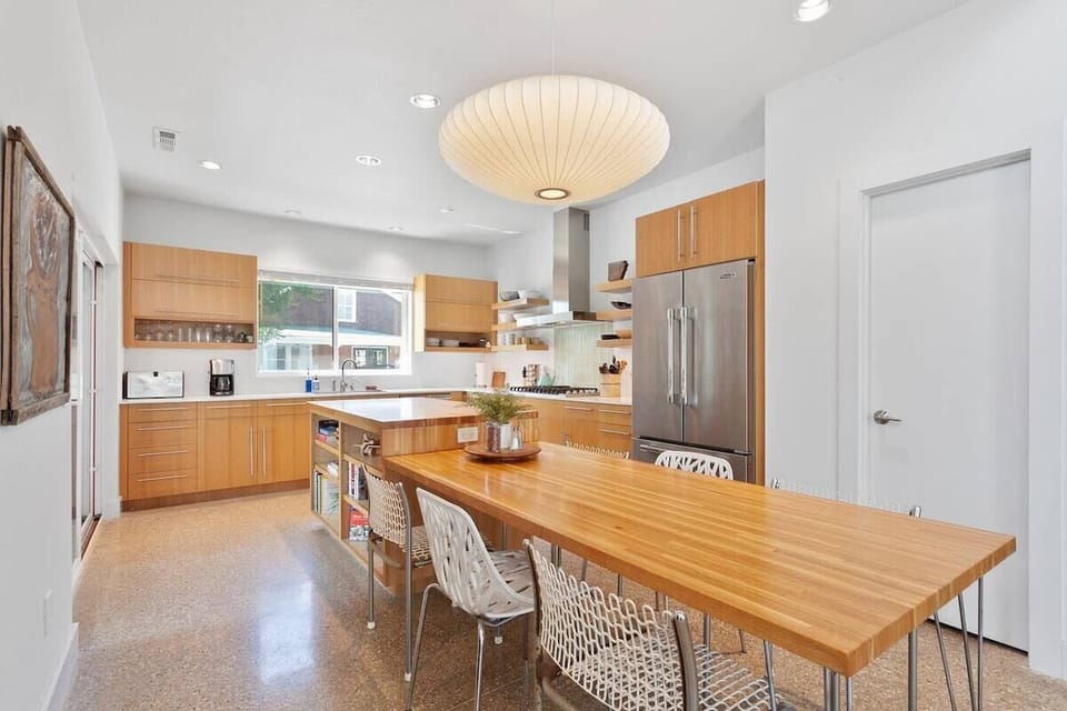 A kitchen of your dreams. Fully stocked for guests, entirely custom, with open shelves, a sleek attached wood table, and plenty of storage.