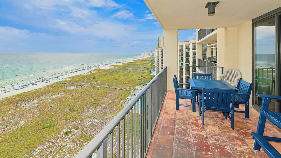 Charming balcony with a lounge chair offers a stunning view of the beach and glistening gulf waters