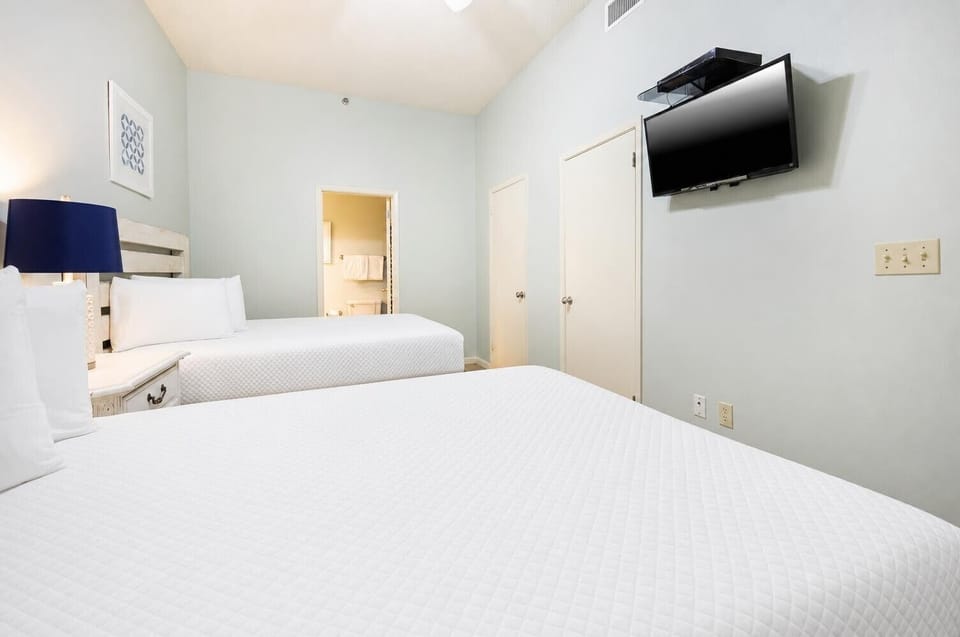 Rest comfortably in this guest room featuring double beds, soft linens, a TV, and adjoining bathroom