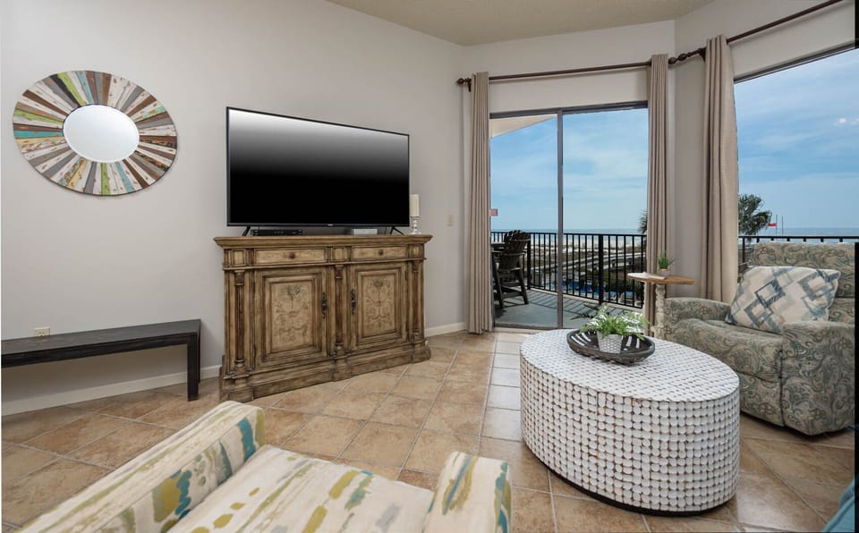 Relax in the inviting living area featuring a large TV, stylish decor, and beachfront balcony