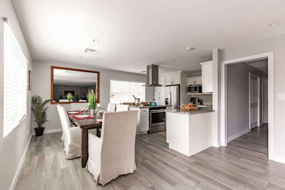 Fully equipped kitchen boasting stainless-steel appliances, an island with bar seating, and formal dining table set to accommodate up to 8 guests.