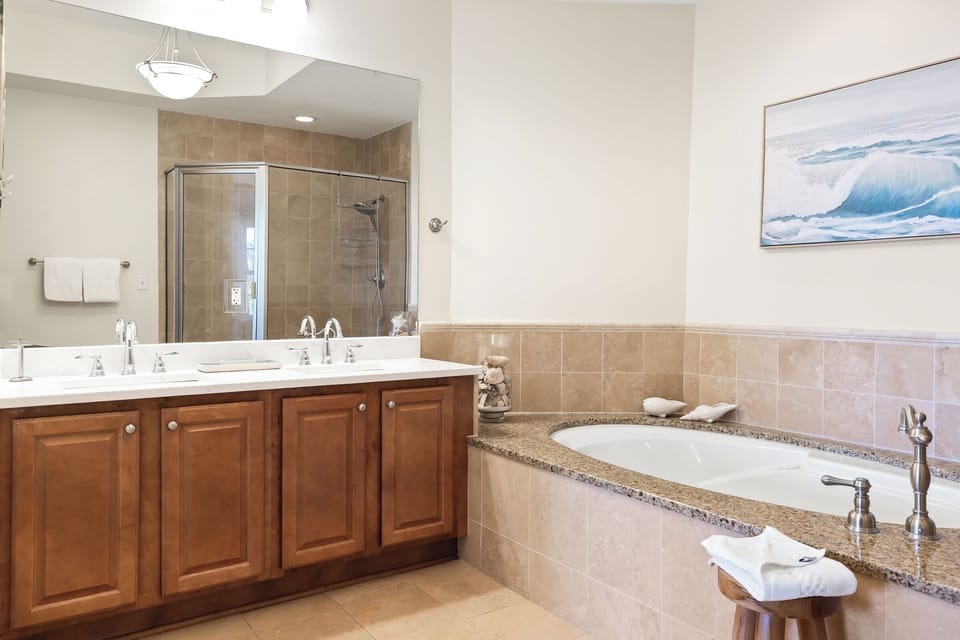 Unwind in your spa-inspired bathroom with dual sinks, a walk-in shower, and a soaking tub framed by warm granite—a perfect retreat after exploring the coast.