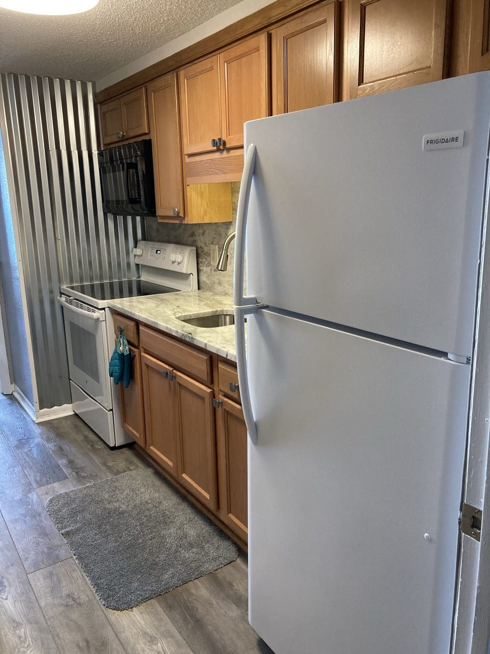 Newly renovated kitchen. Fridge, glass top stove/oven, and microwave.