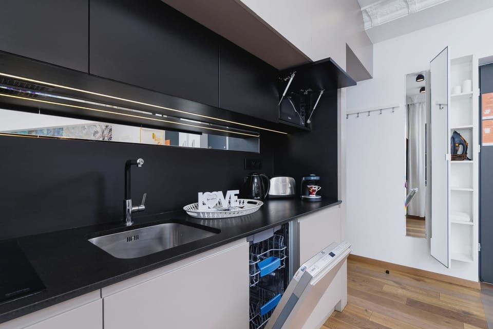A compact kitchenette with black cabinets, a stovetop, and neatly arranged utensils.