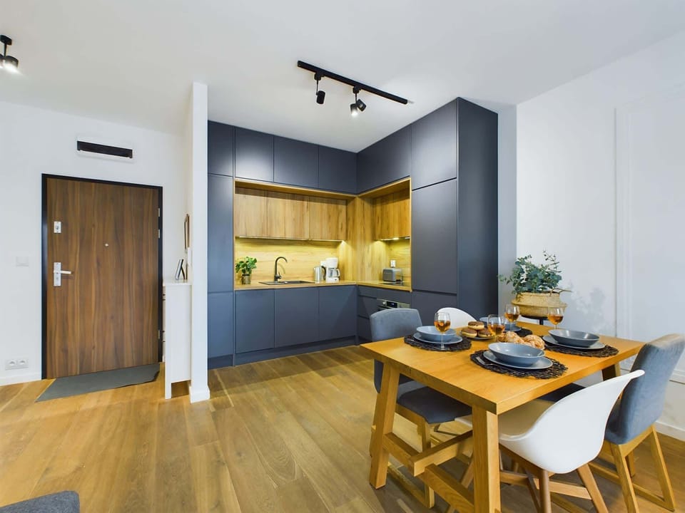 Another view of the kitchenette with open shelving, blue cabinetry, and modern appliances, providing a sleek and functional layout.