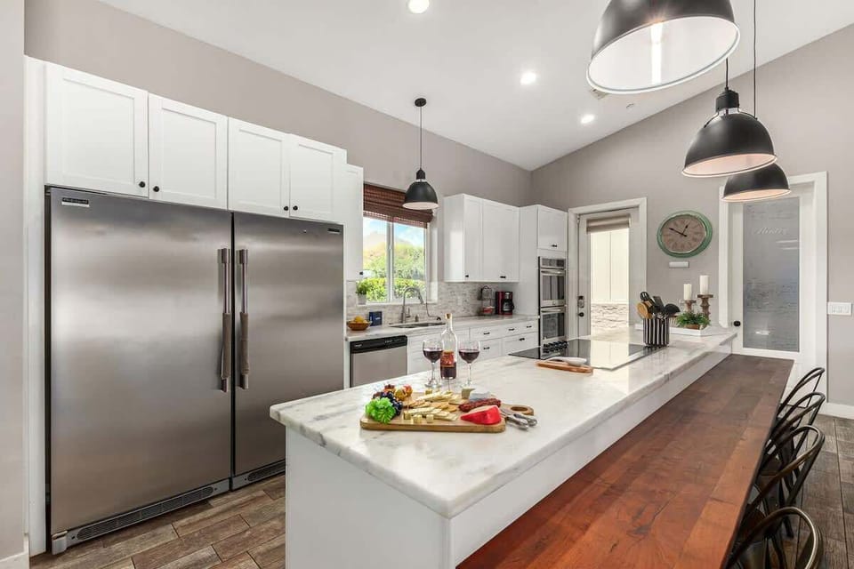 Large kitchen featuring stainless steel appliances, basic cooking essentials, 5 person breakfast bar seating, and a formal dining table for 8.