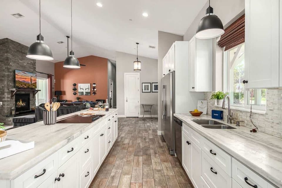 Large kitchen featuring stainless steel appliances, basic cooking essentials, 5 person breakfast bar seating, and a formal dining table for 8.