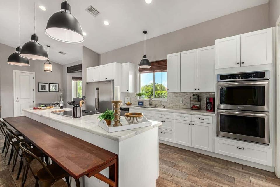 Large kitchen featuring stainless steel appliances, basic cooking essentials, 5 person breakfast bar seating, and a formal dining table for 8.