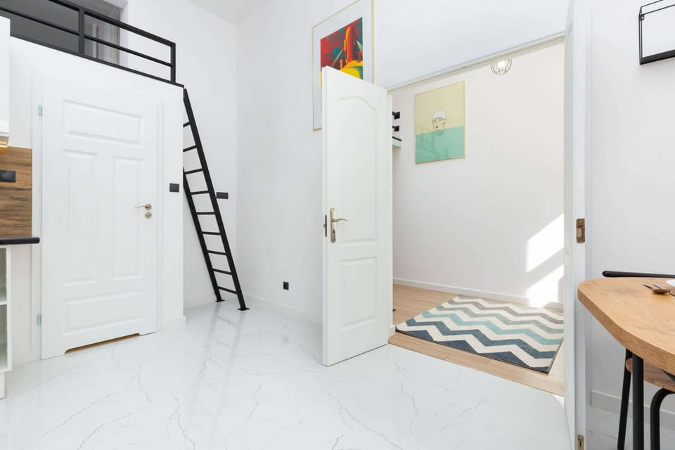 A spacious layout connecting a loft ladder, a table with chairs, and living room elements for a cozy vibe.