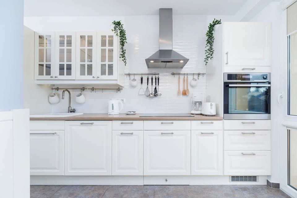 A bright and stylish kitchen with white cabinetry, built-in appliances, and a clean, modern aesthetic. The space feels open and airy.