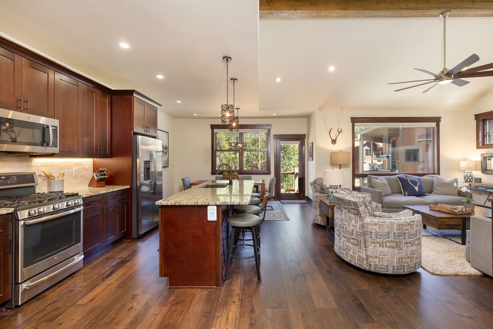 Step into your elegant open-concept retreat where rich wood tones and granite surfaces create the perfect space for cooking and relaxing together.