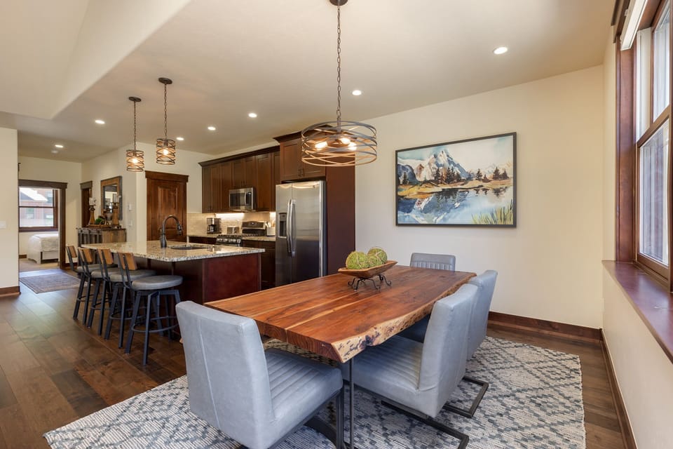 Gather around your stunning live-edge dining table where warm pendant lights create the perfect ambiance for memorable meals together.