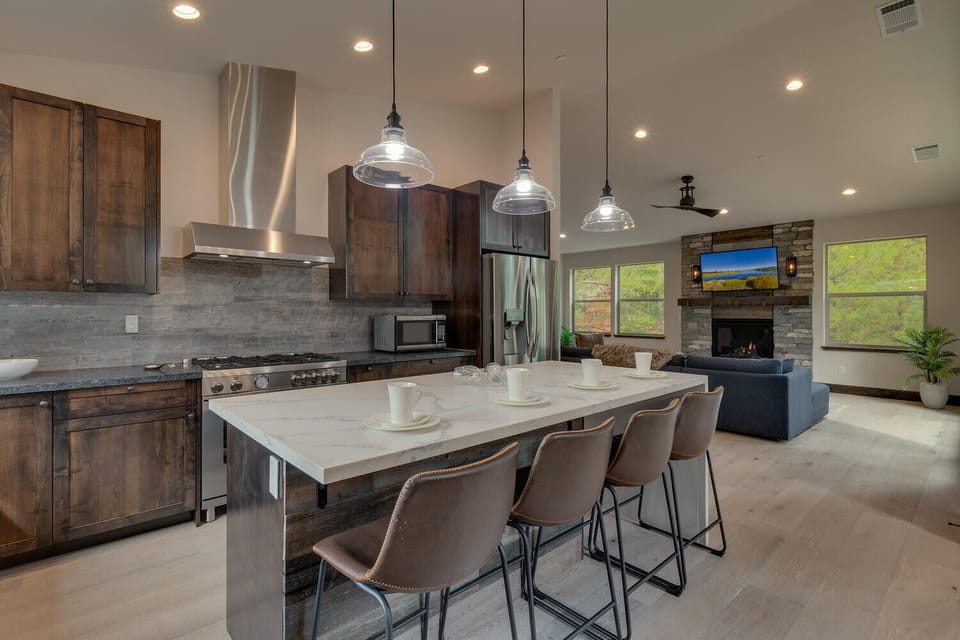 - Open kitchen flows into living room and fireplace  
- Modern appliances and large island with seating  
- Perfect for cooking and entertaining after adventures