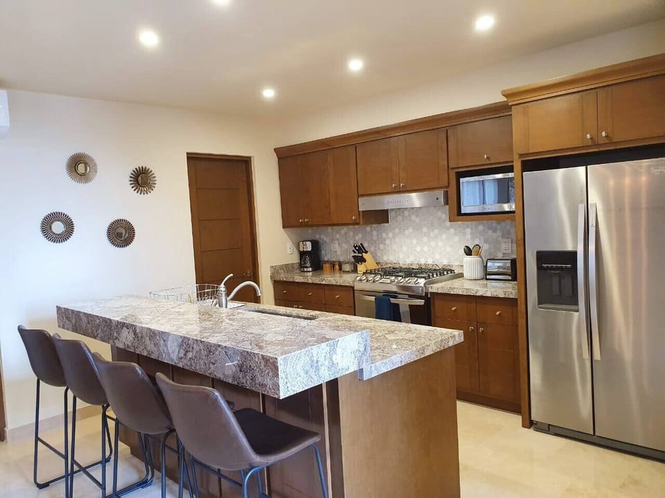 Modern, fully equipped kitchen with stainless steel appliances and breakfast bar seating.
