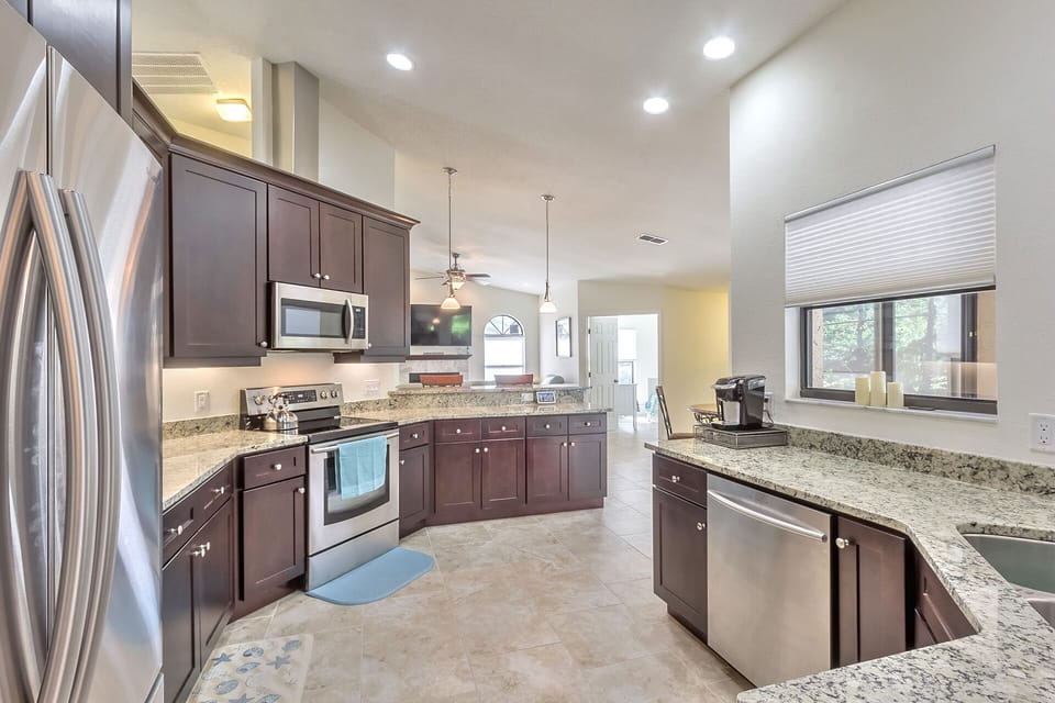 Marble countertops and floor-to-ceiling cabinetry.  Windows overlook pool area.