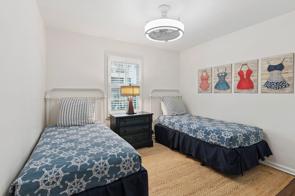 Your nautical twin bedroom offers cozy comfort with maritime charm and cheerful vintage swimsuit artwork that adds personality to your restful retreat.