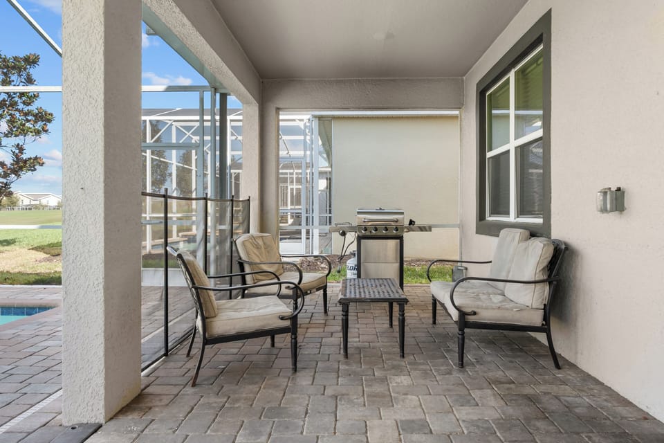 Relax in your private covered patio with comfortable seating and BBQ grill, perfect for outdoor dining while staying cool in the shade.